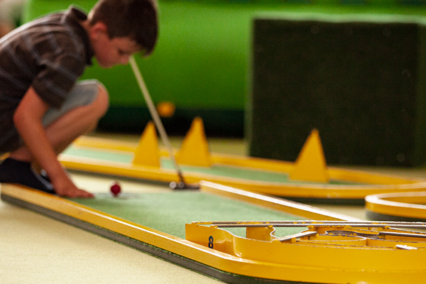 Ein Junge, der Minigolf spielt
