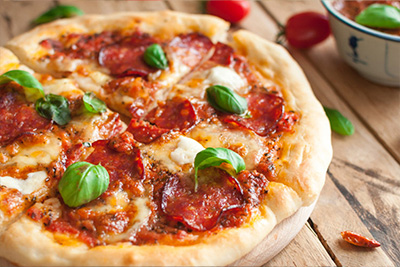 Pizza Eine Salami Pizza dekoriert mit frischem Basilikum